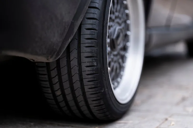 Ein 225 40 R18 Sommerreifen im Vordergrund, sauber und detailliert, bereit für sportliche Fahrzeuge.