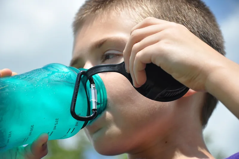Eine Person trinkt während des Sports aus einer robusten Trinkflasche mit Schraubverschluss.