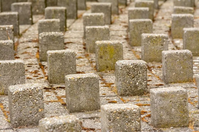 Eine Hand positioniert einen Bewehrungsabstandhalter an einer Stahlmatte auf einer Baustelle.