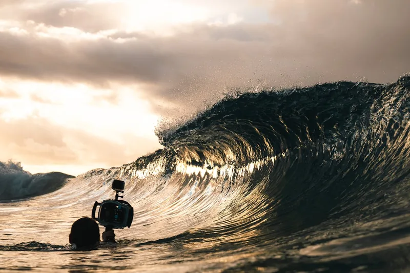 Eine Person surft auf einer Welle, während eine Action-Cam am Surfbrett befestigt ist und filmt.
