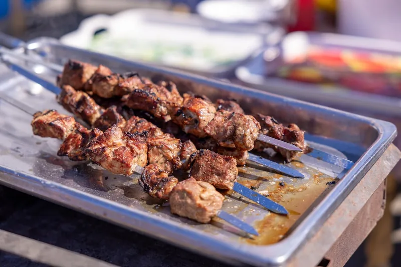 Hochwertiger, flacher Adana-Spieß aus Edelstahl, makellos und bereit für den Grillrost.