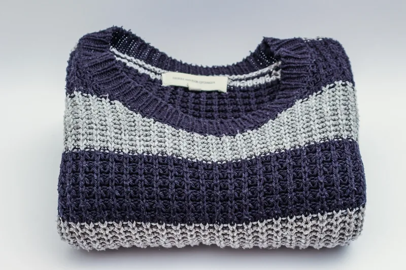 Ein sauber gefalteter Herren Pullover als Produktaufnahme, ideal für Vergleich und Auswahl.