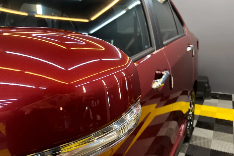 Ein perfekt poliertes Auto in einer Garage, der glänzende Lack spiegelt die Umgebung wider, dank Akku-Poliermaschine.