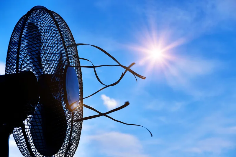 Eine Person nutzt einen kompakten Akku-Ventilator beim Camping, der angenehme Kühlung in der Natur spendet.