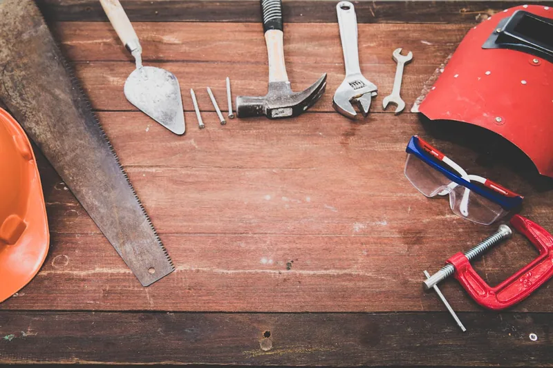 Eine aufgeräumte Werkstatt mit verschiedenen Werkzeugen und Materialresten im Hintergrund, Handwerksszene.