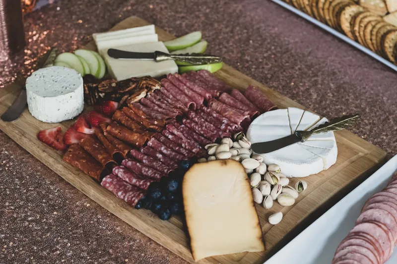 Ansprechend angerichtete Platte mit frisch geschnittenen Wurst-, Käse- und Brotscheiben in einer Küche.