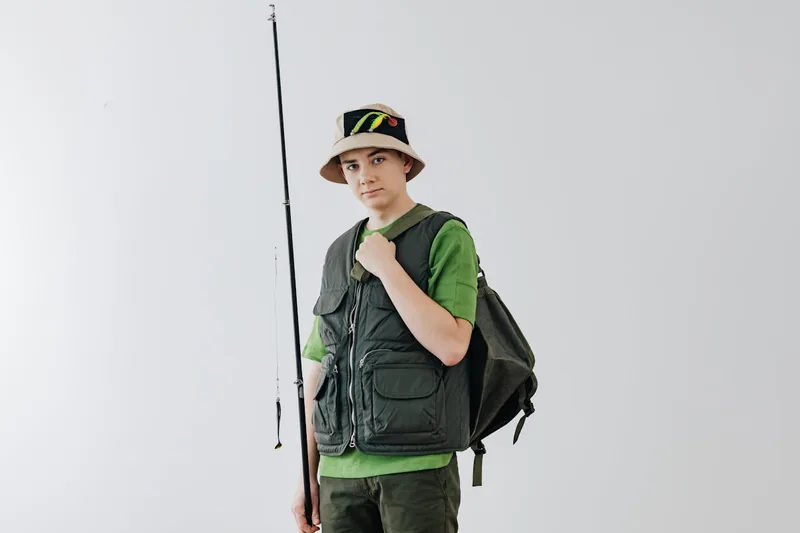 Ein Angler trägt seinen Angelrucksack am Ufer eines Sees, bereit für den Angelausflug.