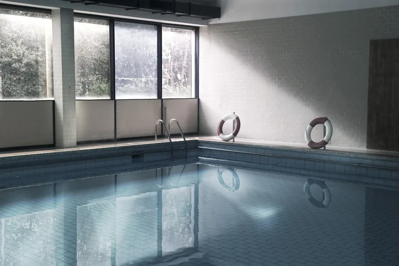 Ein entspanntes Schwimmbad mit Wasseroberfläche und leicht schwimmenden Aqua-Hanteln am Beckenrand.