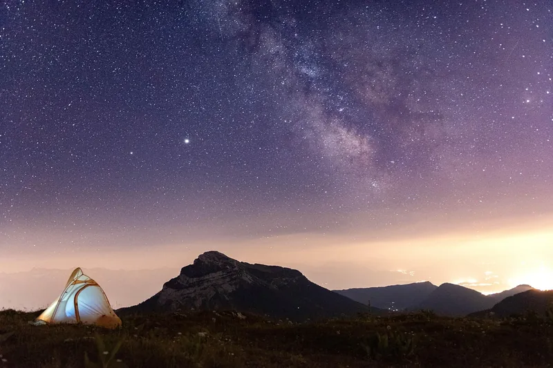 Weite Berglandschaft unter einem atemberaubenden Sternenhimmel, der zur Astrobeobachtung einlädt.