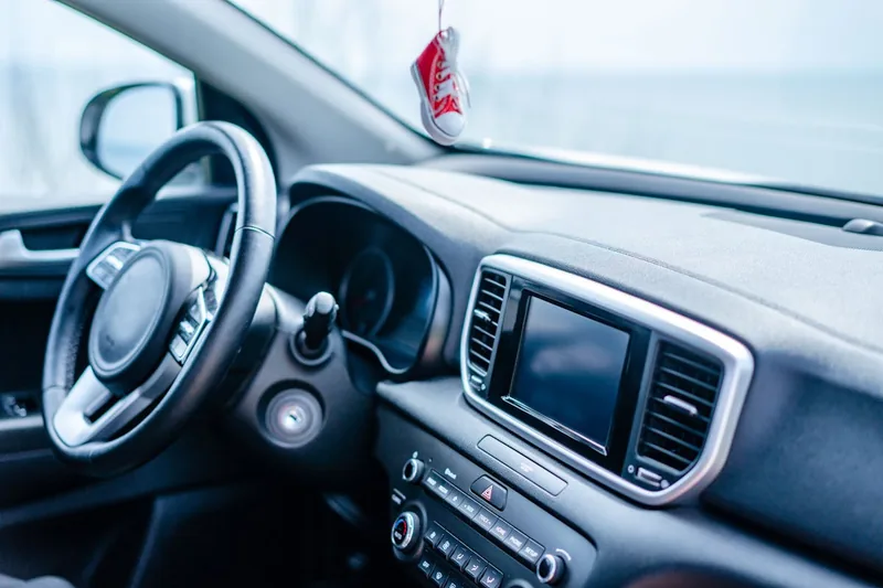 Eine Hand befestigt einen Auto-Lufterfrischer an der Lüftung eines Fahrzeugs, demonstriert die Anwendung.