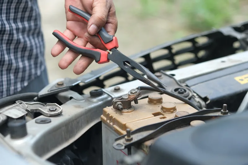 Eine Person installiert oder wechselt eine Autobatterie im Motorraum eines modernen PKW.