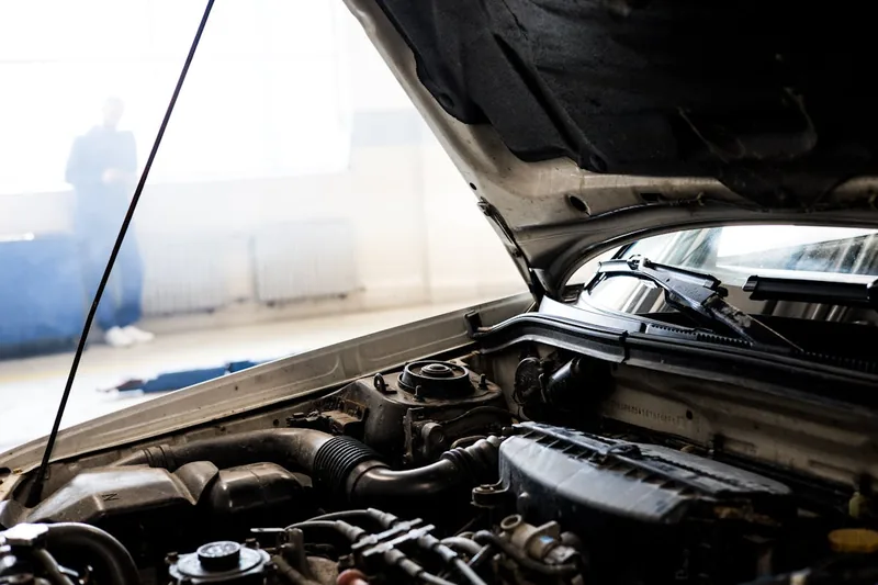 Der offene Motorraum eines Autos in einer sauberen Werkstattumgebung, bereit für Wartungsarbeiten.
