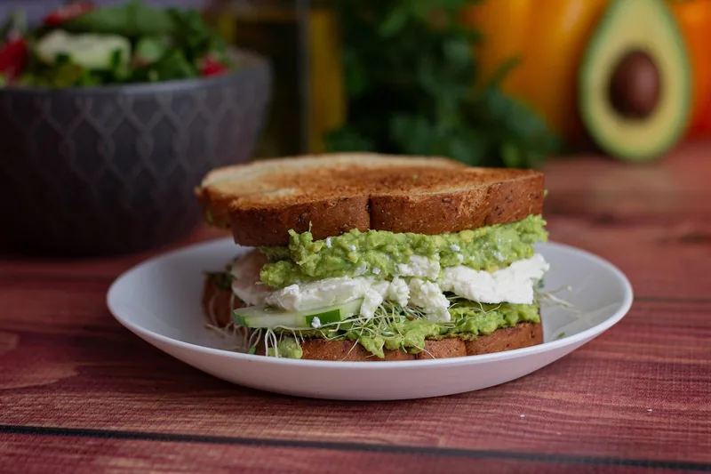 Ein appetitlicher Teller mit frischem Avocado-Toast und weiteren gesunden Zutaten auf einem Holztisch in der Küche.