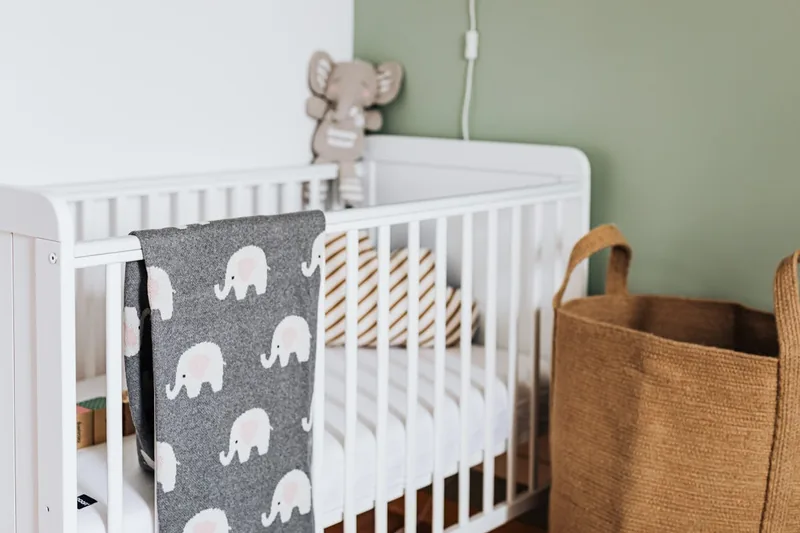 Ein stilvolles Holz-Babybett als klares Produktfoto, fokus auf Design und Material.