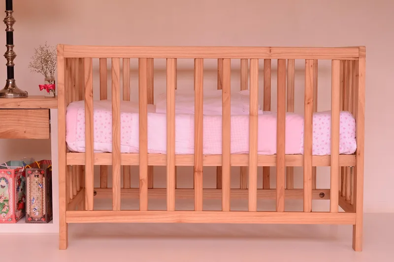 Eine fürsorgliche Hand legt ein friedlich schlafendes Baby sanft in das gemütliche Babybett.