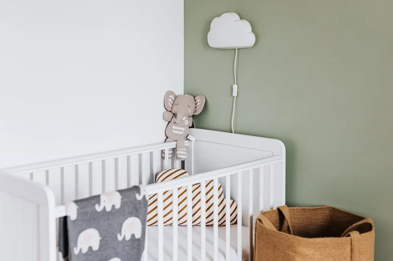 Ein liebevoll eingerichtetes Kinderzimmer mit einem Babybett als Mittelpunkt, strahlt Geborgenheit aus.