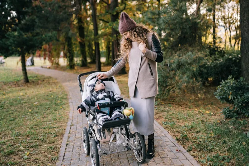 Ein Kinderwagen mit Baby Fußsack in einem sonnigen Herbstpark, bereit für einen gemütlichen Spaziergang.