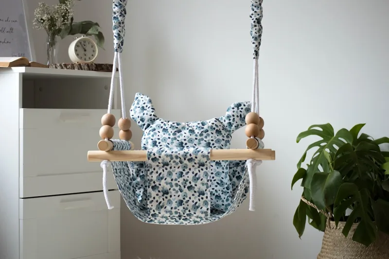 Eine moderne automatische Babyschaukel mit verschiedenen Funktionen vor hellem Hintergrund.