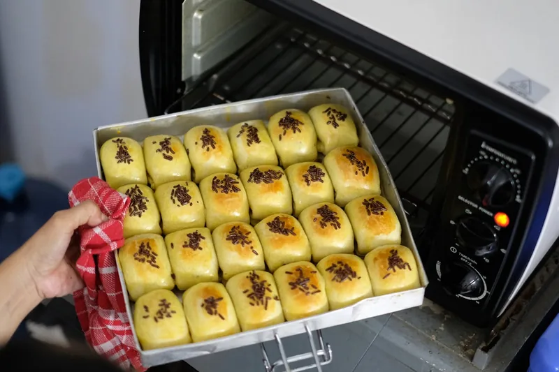 Duftende, goldbraune Brötchen auf einem ausziehbaren Backblech, bereit zum Genießen in der Küche.