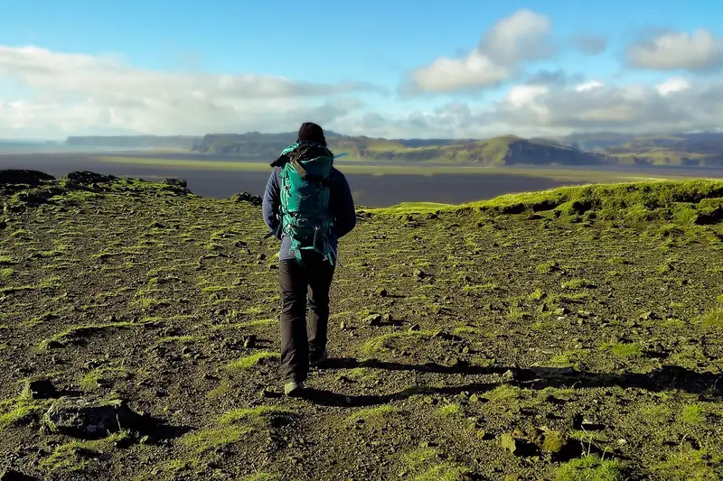 Eine Person passt die Schultergurte ihres Backpacking-Rucksacks während einer Wanderung aktiv an.