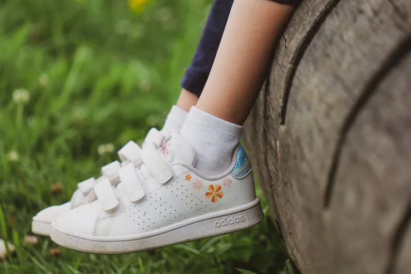 Ein Kind beim Spielen im Freien, trägt Barfußschuhe, die natürliche Bewegungsfreiheit unterstützen.
