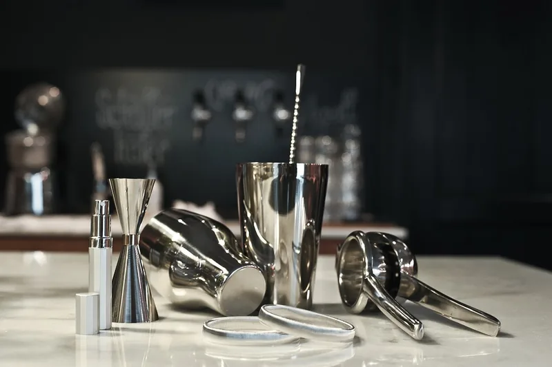 Hochwertiges Edelstahl Barkeeper-Set auf dunklem Hintergrund, bereit zum Mixen edler Drinks.