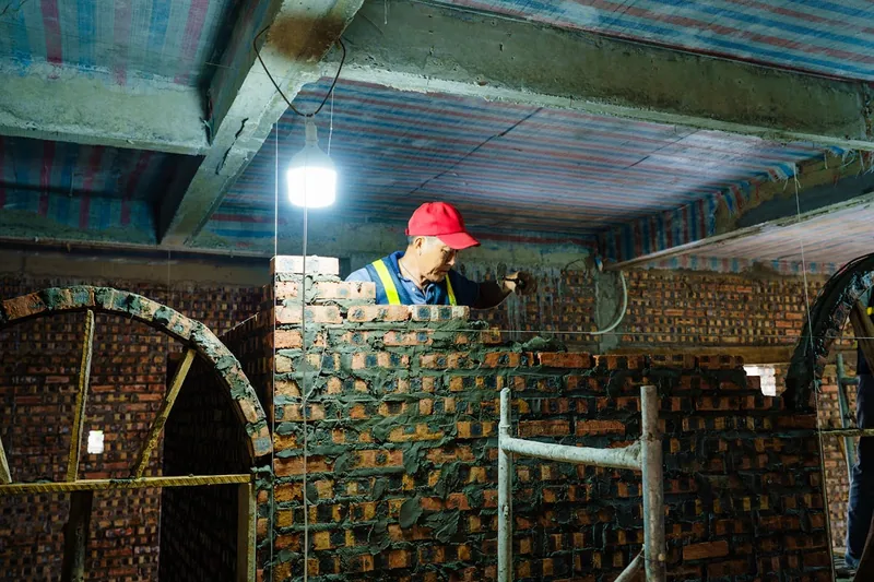 Eine Person richtet einen Baustrahler auf einer Baustelle aus, um den Arbeitsbereich optimal zu beleuchten.
