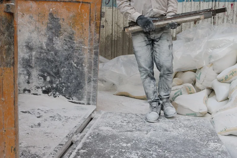 Eine Person befüllt einen Big-Bag-Sack mit Bauschutt auf einer Baustelle, zeigt praktische Anwendung.
