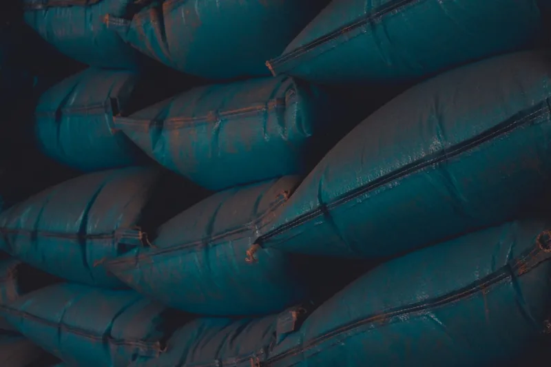 Mehrere gestapelte Big-Bag-Säcke in einem Industrielager, symbolisieren effiziente Logistik.