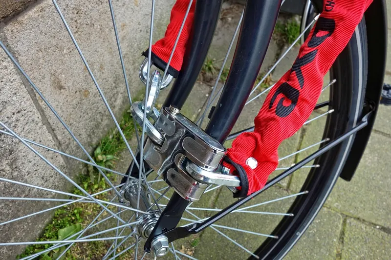 Person sichert Fahrrad mit einem langen Schloss.
