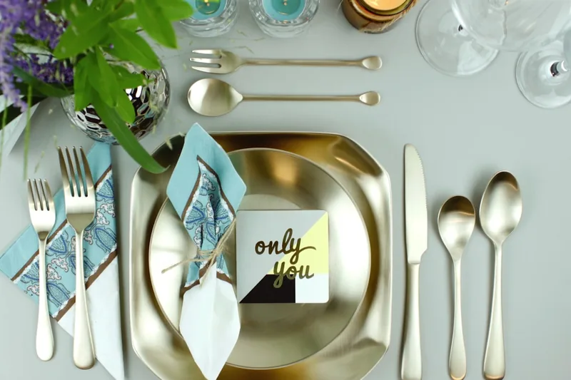 Ein vollständiges, glänzendes Besteckset elegant auf neutralem Hintergrund präsentiert.