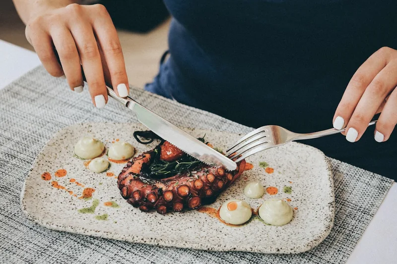 Eine Person hält Besteck beim Essen einer Mahlzeit, Fokus auf ergonomisches Essbesteck.