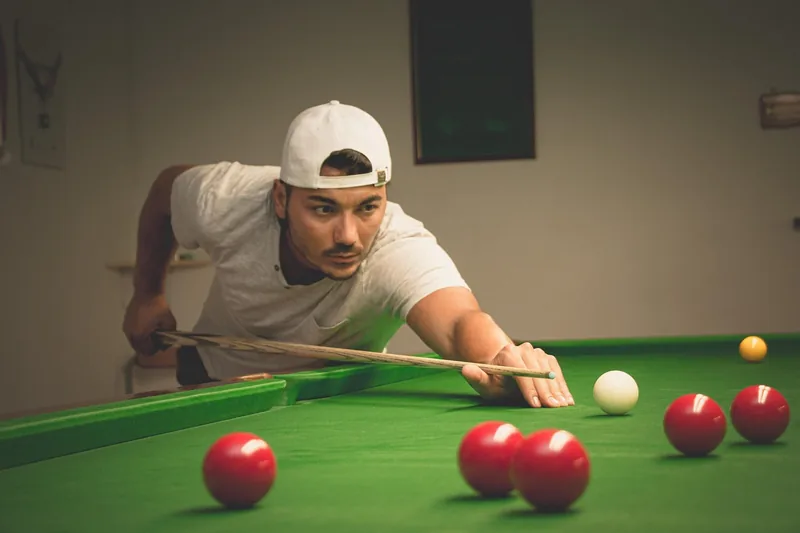 Person spielt Billard mit einem professionellen Queue am Tisch.