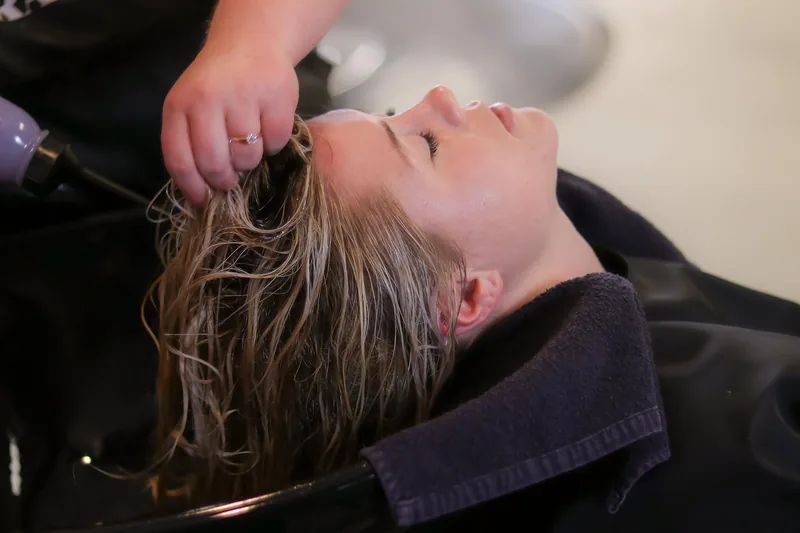 Hand trägt Biotin-Shampoo auf nasses Haar auf