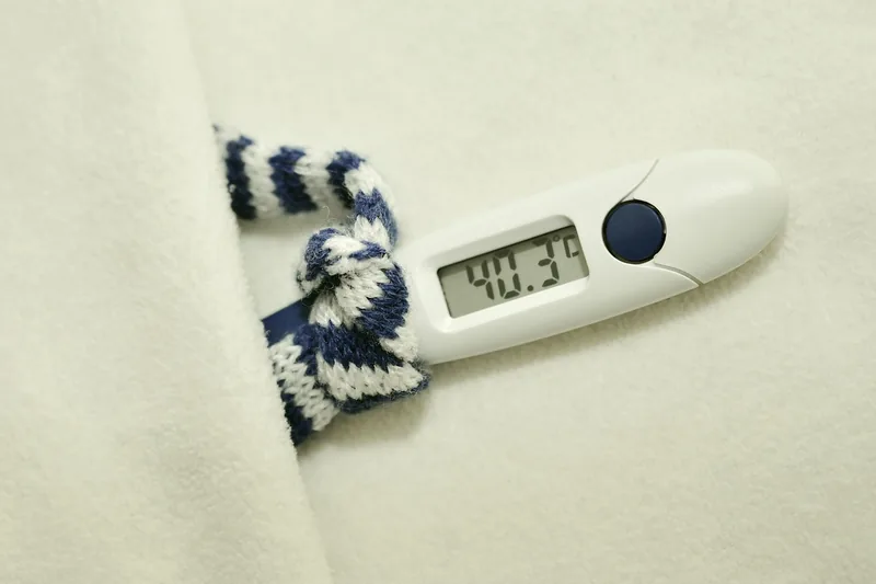 Eine Hand hält ein Bluetooth-Thermometer zur Messung der Körpertemperatur.