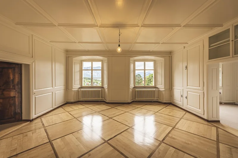 Ein frisch gereinigtes Wohnzimmer mit glänzendem Parkettboden, das ein sauberes Wohnambiente widerspiegelt.