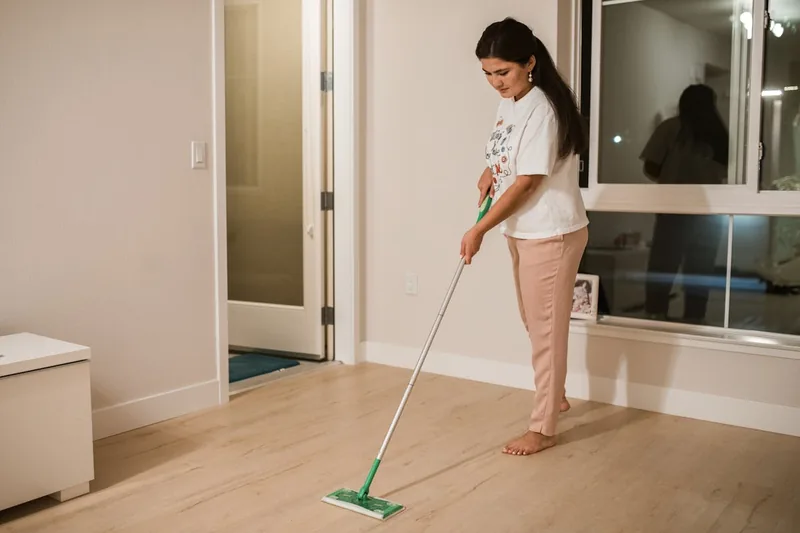 Eine Person wischt einen glänzenden Holzfußboden mit einem ergonomischen Bodenwischer.