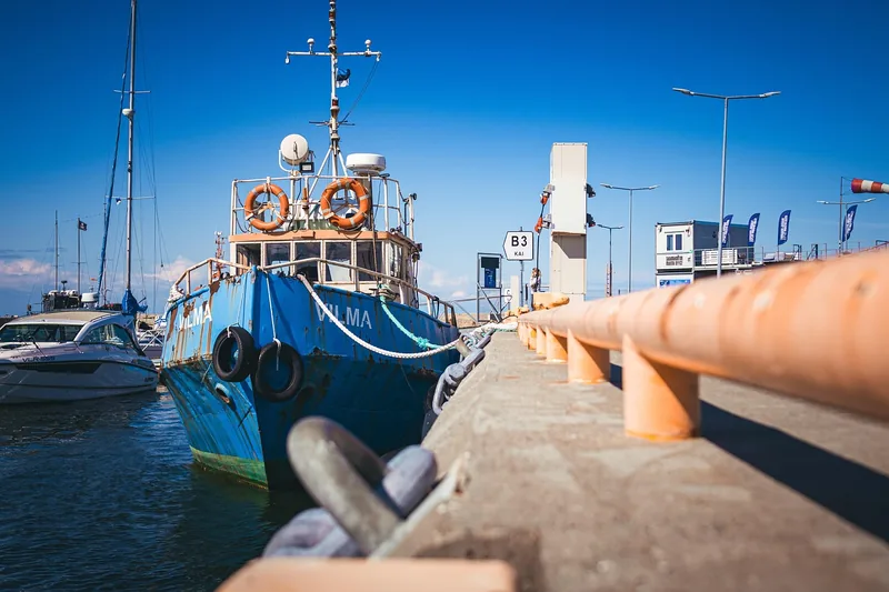 Ein glänzendes Boot liegt vertäut in einem sonnigen Hafen.