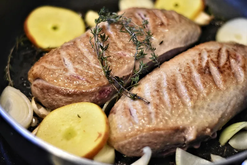 Ein perfekt gebratener, saftiger Braten auf einem Schneidebrett, umgeben von Kräutern.