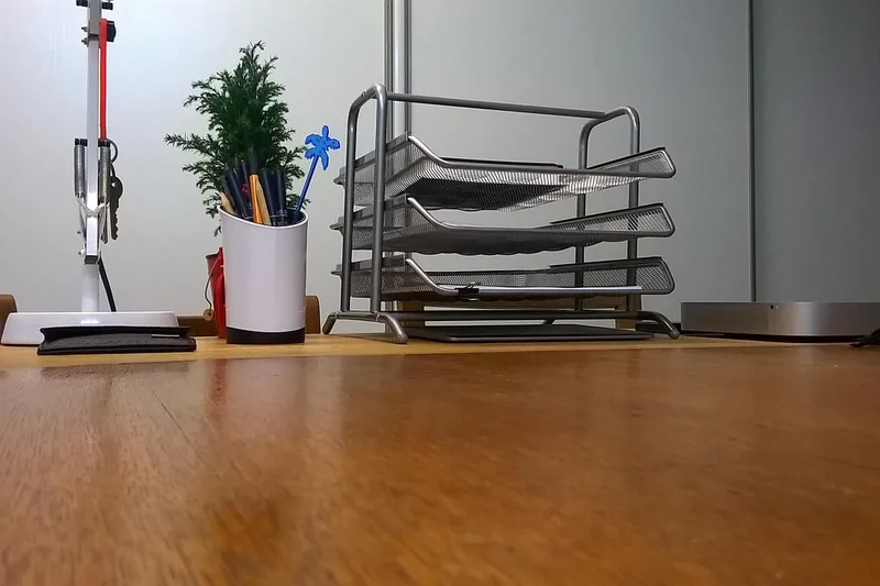 Eine Person sortiert Dokumente und Papiere in eine stapelbare Briefablage, um den Schreibtisch effizient zu organisieren.