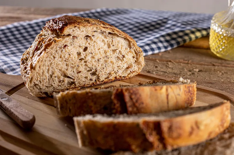 Ein Teller mit duftendem, frisch aufgeschnittenem Brot, angerichtet auf einem Holztisch in einer gemütlichen Küchenszene.