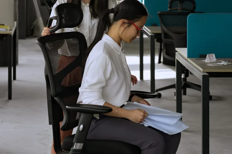 Eine Person stellt die Rückenlehne eines Bürostuhls ein, um eine optimale Sitzhaltung zu finden.