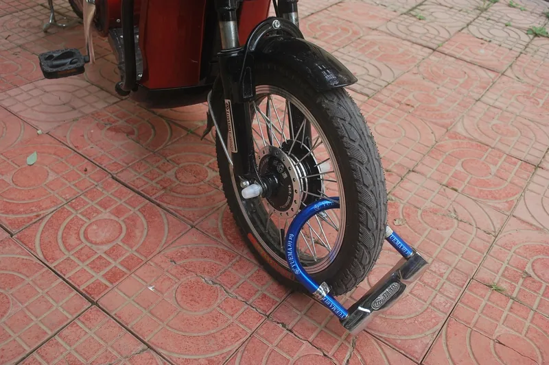 Eine Person sichert ihr Fahrrad mit einem stabilen Schloss an einem Fahrradständer in der Stadt.