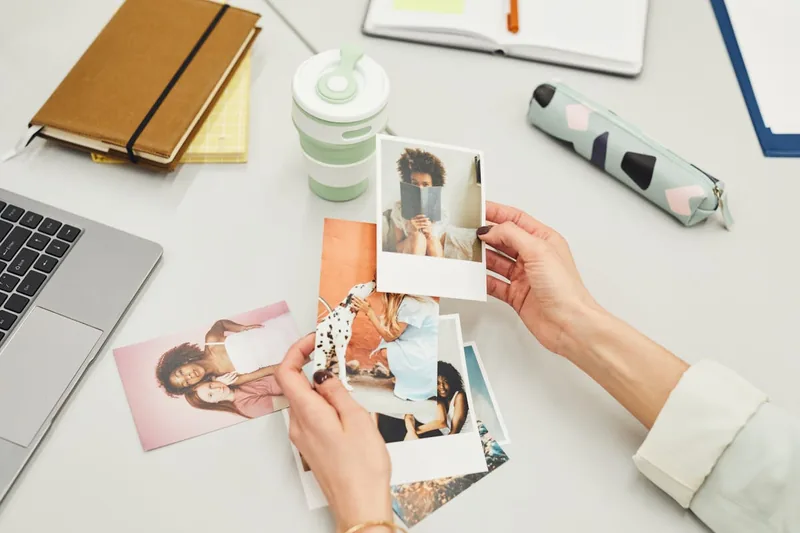 Ein aufgeräumter Schreibtisch im Home-Office mit fertig gedruckten Fotos und Dokumenten.