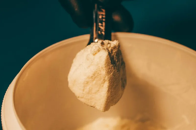 Nahaufnahme von feinem Casein-Proteinpulver, das in einem Messlöffel liegt und seine Textur zeigt.