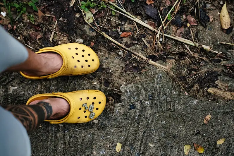Eine Person trägt bunte Clogs Schuhe bei der Gartenarbeit, praktisch und bequem für draußen.