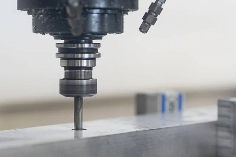 Eine Person überwacht konzentriert die Bearbeitung eines Holzwerkstücks mit einer CNC Fräse.