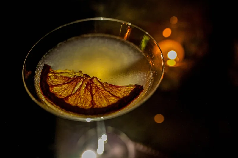Eine Hand hält ein Cocktailglas während der Zubereitung eines Mixgetränks, zeigt die praktische Anwendung.