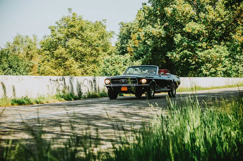 Ein elegantes Cabriolet parkt am Straßenrand bei Sonnenuntergang, vor einer atemberaubenden Landschaft.