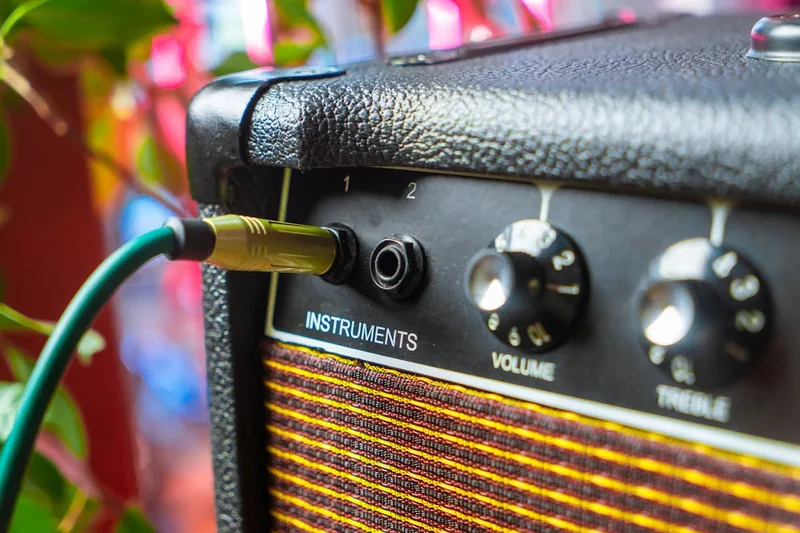 Eine Hand schließt ein Instrumentenkabel an eine Di-Box an, für eine stabile Audioverbindung.